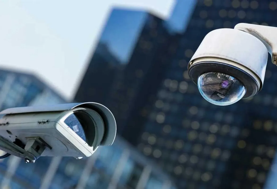 Dome and bullet CCTV cameras mounted on a glass office building